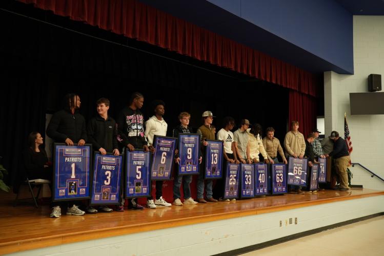 Senior football players line up across the stage after being presented with their framed jerseys at the OCHS awards ceremony in the cafeteria on Monday night. (Saylor Williams/The Oglethorpe Echo)
