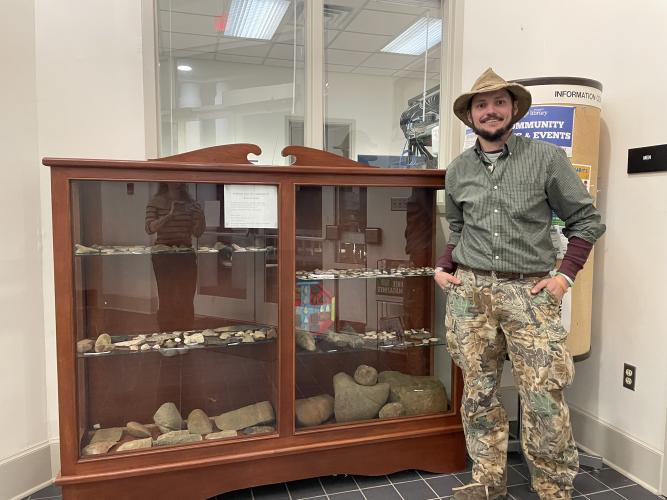 Kane Dieball stands with part of his collection of Native American artifacts on display at the Oglethorpe County Library. Dieball said he often finds arrowheads and other artifacts when he’s hunting. (Dakota Meeks/The Oglethorpe Echo)