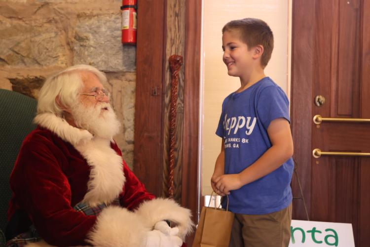 Weston Stewart, who is 8 years old, tells Santa what he wants for Christmas at the Christmas Marketplace at the Historic Crawford Depot on Sunday. In addition to shopping, visitors could take a picture with Santa during the annual three-day event. (Photo/ Sarah Coyne)