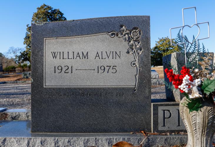 A close-up shot of the headstone of William Alvin Pitts, which reads "Loving Husband, Father, and Pop" in Lexington, Georgia on Monday, Jan 20, 2025. The cemetery where Alvin ad his wife Doris are buried is directly behind the former Minit Mart Service and Liquor Store. (Photo/Felix Scheyer)
