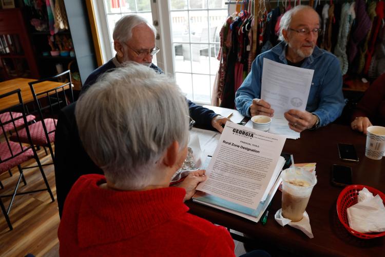 Linda Parish reads the Rural Zone Designation plan at the Lexington Downtown Development Authority board meeting at Town and Country Kafe on Thursday. The DDA, which includes Ronnie Boggs (left) and Tom Thon (right), discussed revisions to the master plan, updates to the community center and rural zone designation. (Photo/Libby Hobbs)