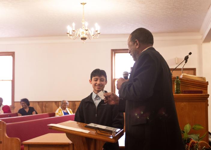 Elian Castellanos-Contreras of Oglethorpe County Middle School recieves a check from Reverend Dr. R. A. Hunter for placing in the Concerned Men of Oglethorpe County's annual MLK Essay Contest at the annual Dr. Martin Luther King, Jr. Program held at Mt. Zion Baptist Church in Stephens, Georgia on Jan. 20, 2025. The annual program first began in 2005 and aims to bring the community and youth of Oglethorpe county together in unity, modeled after the values of Dr. Martin Luther King Jr. himself. (Photo / Lux C