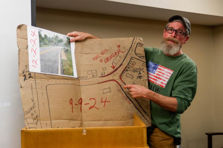 Brad Johns, a resident of Oglethorpe County’s Almond Drive, speaks during a Board of Commissioners meeting within the Tax Commissioner’s Office in Oglethorpe County on Monday, Feb. 3, 2025. Johns uses homemade cardboard diagrams to emphasize the issues he has with the state of Almond Drive. (Photo/Felix Scheyer)