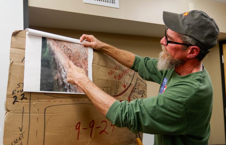 Brad Johns, a resident of Oglethorpe County’s Almond Drive, speaks during a Board of Commissioners meeting within the Tax Commissioner’s Office in Oglethorpe County on Monday, Feb. 3, 2025. Johns uses homemade cardboard diagrams to emphasize the issues he has with the state of Almond Drive. (Photo/Felix Scheyer)