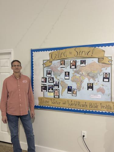 (Jet Rawls/The Oglethorpe Echo) Paul poses for a photo by a map showcasing the leaders of the WorldReach campuses around the world.