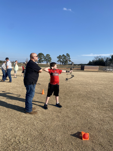 Will Elder coaches fifth grader Ty Crowe behind the line at the OCMS soccer fields on Feb. 9. Crowe is practicing for the state archery match on May 3 at the Rock Eagle 4-H Center. (Photo/Anna Izquierdo)