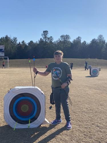 Seventh grader JT Mathews retrieves his arrows from a 30-meter target at the OCMS soccer fields on Feb. 9. Mathews is practicing for the state archery match on May 3 at the Rock Eagle 4-H Center. (Photo/Anna Izquierdo)