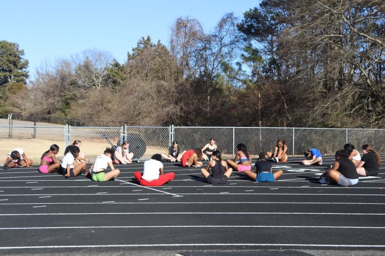 The OCHS girls track team is warming up by stretching before their practice on Tuesday, Feb. 4 on the track at Oglethorpe County High School. The Patriots begin their season on Saturday, Mar. 1 in the Curahee Invitational at Stephens County High School. (Photo/ Kayda Hammock)