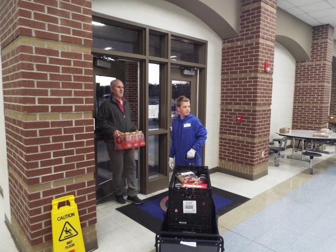Turley Howard and student volunteer Charlie prepare groceries to help families load them into their vehicles during the mobile food pantry on Thursday, Feb. 20. (Photo/Luis Vaquero)