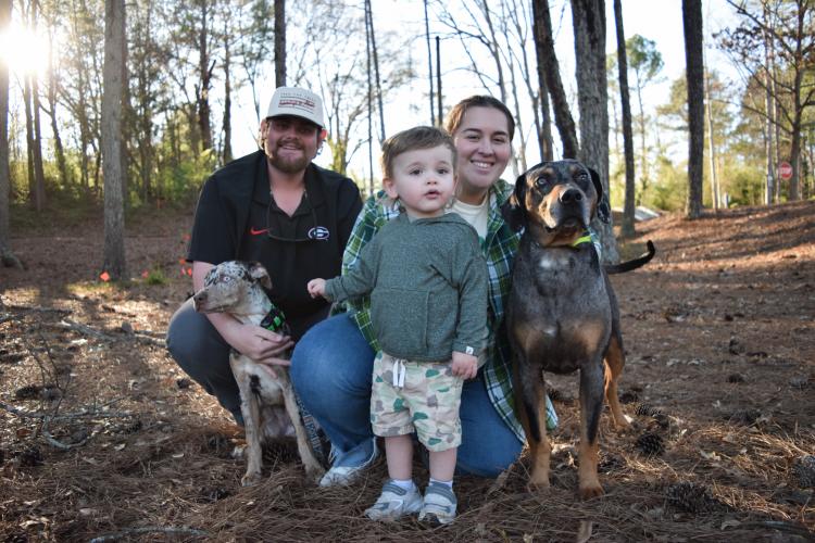 Lucas (from left), Stetson and Brooke Holcombe stand with their two catahoula leopard dogs, Delta Dawn (left) and Boone (right), at the UGA Intramural Fields last month. The Holcombes, who live in Winterville, have started a hunting business around their dogs. (Photo/Jesse Wood)