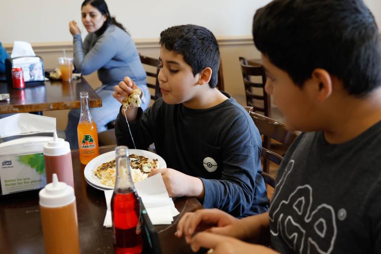 Abdiel Ramirez blows on hot food at the El Mana 2 restaurant grand opening at 777 Athens Road in Lexington on March 19. El Mana 2 is a new Salvadoran restaurant serving pupusas, tamales and pollo rostizado. (Photo/Libby Hobbs)