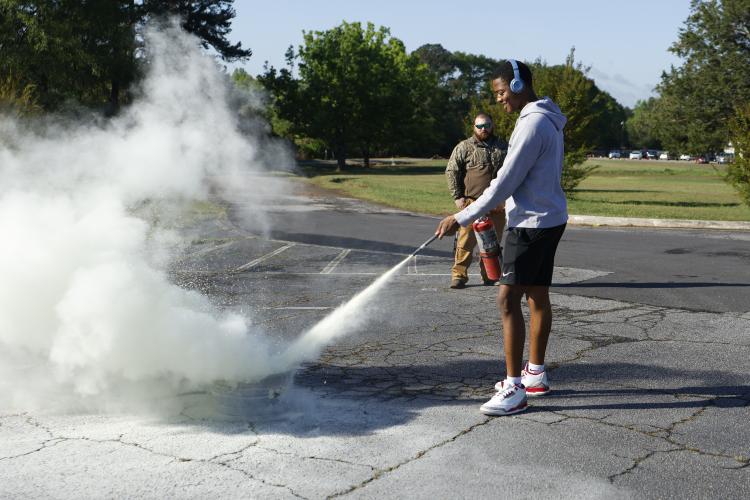 Malachi Bryant, an OCHS senior, sprays a fire extinguisher during a demonstration at the Ghost Out on Friday. Students also operated driving simulators and participated in other demonstrations during the event. (Photo/Frankie Hennessy)