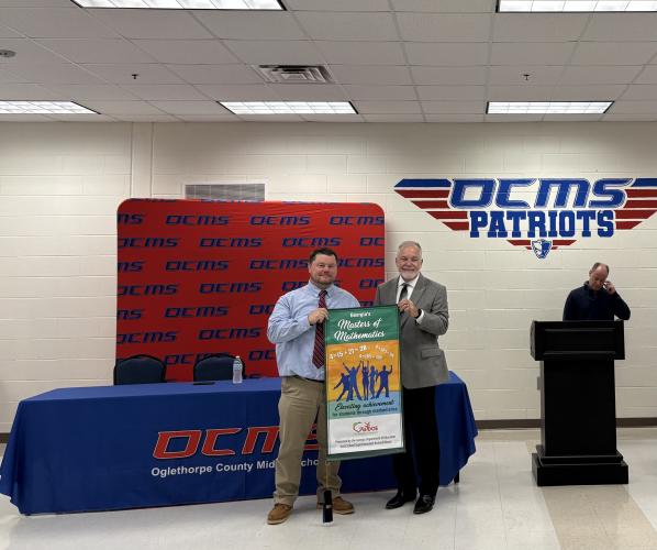 OCMS Principal Mack Baldwin (left) stands with State Superintendent Richard Woods while holding the Georgia Masters of Mathematics banner. The banner was awarded to OCMS for the high scores in last year’s eighth-grade accelerated math course. (Photo/Emery Pikel)