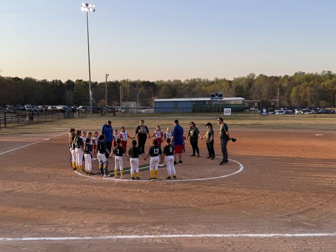 The Oglethorpe County Patriots and Franklin County Mighty Ducks stand in the center of the softball field to pray last Thursday following the Patriots’ 8-0 loss. Despite the loss, Patriots coach Courtney Kitchens has noticed improvements in her players' softball fundamentals. (Photo/Anna Izquierdo)
