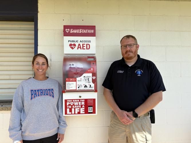 District nurse Kristina Turner (left) and EMS director Josh Robinson stand with the new SaveStation at OCHS. “One of the goals of this project was to try to get AEDs as accessible to people in the county as possible,” Robinson said. (Photo/Emery Pikel)