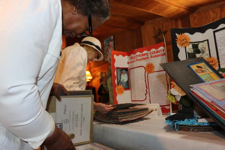 Barbara Cabaniss (background) and Margaret Sims (front) look at historical documents and presentations that were on display at the 50th anniversary of the Oglethorpe County Retired Educators Association on April 7. Paige Clarke/The Oglethorpe Echo