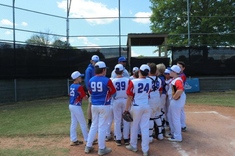 Both teams huddle on home plate with Coach Michael White for a team chant following the home team's 7-1 win on April 12. The rescheduled game led to White's decision to combine the three Major League teams into two. (Photo/Anna Izquierdo)