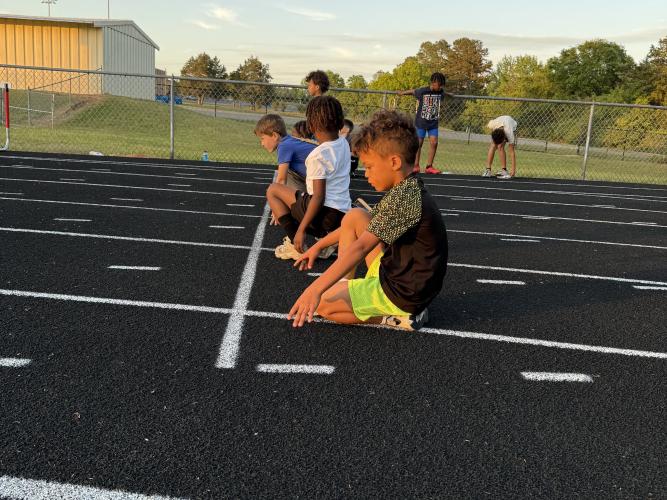 Tevin Sintyl, 8, kneels on the track in preparation for a 100 meter sprint that determines the 8U 4x100 meter relay team for the North Georgia Youth Track and Field League Championship meet. Sintyl competed in the relay last month with teammates Chase Turner, Ky Faust and Jordan Lumpkin, and the team ran 1:12.74. (Photo/Anna Izquierdo)