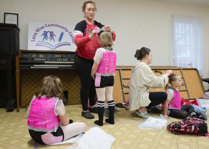 From left: dancers Ava Grace Gay, Delaney Wiebe, and Josie Blaylock try on costumes for their tap and jazz combo class's upcoming performance at the Lena Wise Community Center in Crawford, Ga on April 7, 2025. Mothers Angela Wiebe (left) and Braylee Poole (right) help their daughters try on bows. The dancers are a part of Jessica's School of Dance, a complete dance program for young girls of all ages led by instructor Jessica Palmer. (Photo / Lux Corrona)