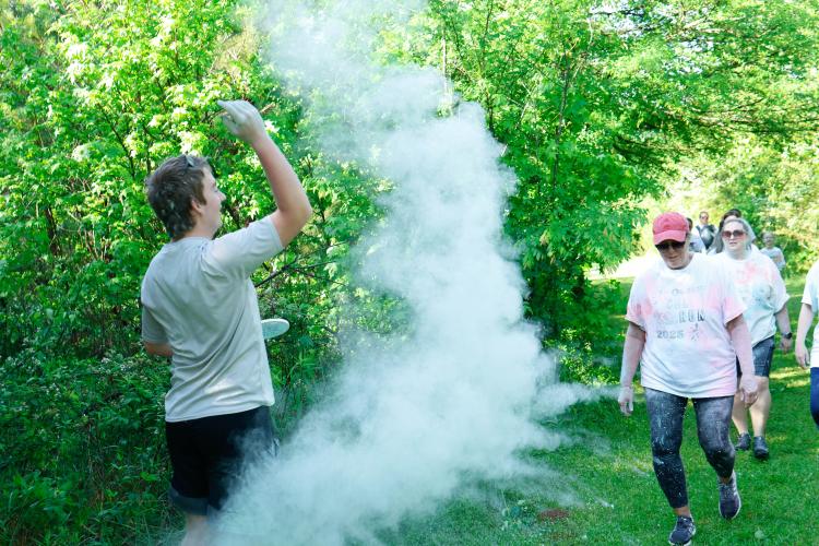 Jake Huff, a sophomore student at Oglethorpe County High School, throws chalk at runners as they run along the Oglethorpe County High School Color Run in Oglethorpe County, Georgia, on Saturday, April 26, 2025. In an attempt to avoid the colored chalk blowing back into his face, Huff moved further down the course. Sadly, his movement had no effect on the amount of chalk that coated him with each throw. (Photo/Felix Scheyer)