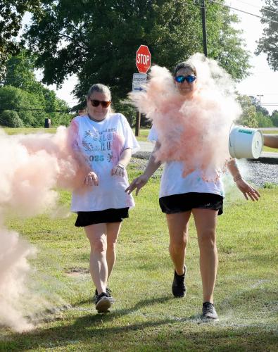 Two Color Run participants are hit with buckets of colorful chalk from both sides as they prepare to cross the finish line of the Oglethorpe County High School Color Run course at the Oglethorpe County High School in Oglethorpe County, Georgia, on Saturday, April 26, 2025. In addition to getting covered in chalk powder, the annual OCHS Color Run allows for members of Oglethorpe County to come together for a morning of colorful camaraderie while supporting a local cause able to directly affect their own comm