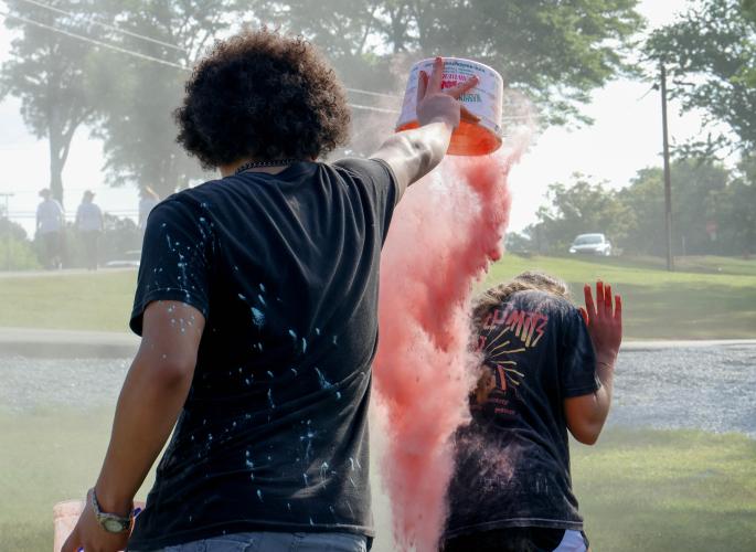Aydan Aziz, a sophomore student at Oglethorpe County High School, throws chalk at another student helping to run the Color Run at the finish line of the Oglethorpe County High School Color Run course at the Oglethorpe County High School in Oglethorpe County, Georgia, on Saturday, April 26, 2025. After finishing the run, participants would be greeted by the remaining NHS members, who would cover those crossing the finish line in a shower of colored chalk. (Photo/Felix Scheyer)