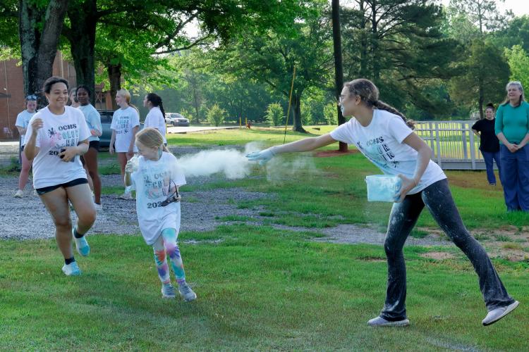 Abby Hormeku, a sophomore student at Oglethorpe County High School, throws chalk at a race participant as they cross the finish line of the Oglethorpe County High School Color Run course at the Oglethorpe County High School in Oglethorpe County, Georgia, on Saturday, April 26, 2025. (Photo/Felix Scheyer)