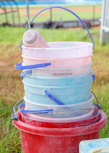 A stack of colorful chalky buckets and a squeeze bottle sit next to the finish line after the Oglethorpe County High School Color Run at the Oglethorpe County High School in Oglethorpe County, Georgia, on Saturday, April 26, 2025. After the race concluded, members of the OCHS NHS gathered together to congratulate and thank those who participated, before working together to wash the buckets, bottles, and other dirtied items clean of the chalk. (Photo/Felix Scheyer)