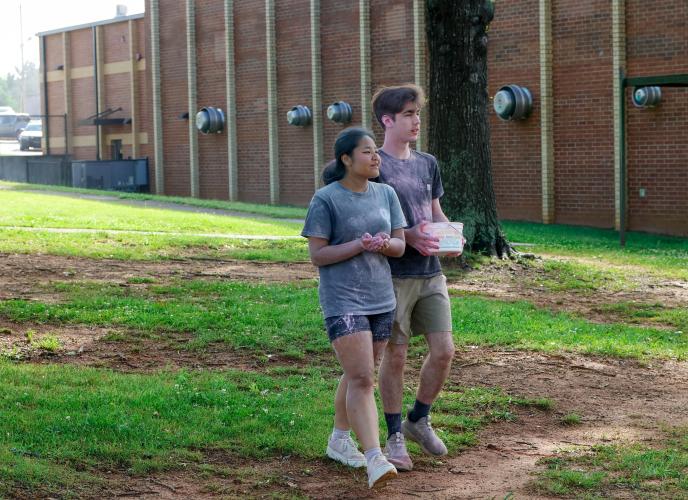 Su Moo (left), a senior student at Oglethorpe County High School and Bailey Abrams, a junior student at Oglethorpe County High School, walk together while helping to clean up after the Oglethorpe County High School Color Run at the Oglethorpe County High School in Oglethorpe County, Georgia, on Saturday, April 26, 2025. “This is kind of [Mrs. Yauck’s] big main event,” said Abrams. “…everyone just kind of got together, just talked it over, and got it set up.” (Photo/Felix Scheyer)