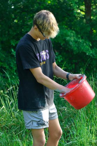 Aidan Dellinger, a junior student at Oglethorpe County High School, reaches into his bucket to grab a handful of chalk while waiting along the Oglethorpe County High School Color Run course at the Oglethorpe County High School in Oglethorpe County, Georgia, on Saturday, April 26, 2025. Both Dellinger’s mother Alicia Dellinger, an economics teacher at OCHS, and grandmother Shirley Smith ran in the Color Run. Dellinger was very enthusiastic in his chalk throwing when either came within his range. (Photo/Felix
