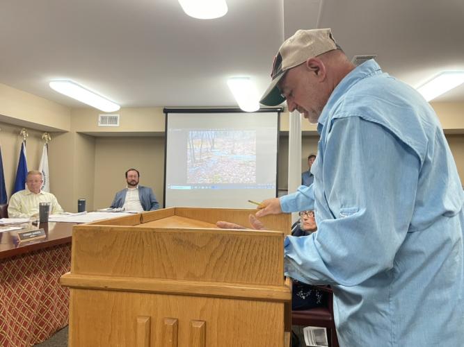 Daniel Rotberg shows photos of gravel and mud that flowed onto his property that he said was runoff from Vinh Tran's property. Rotberg voiced his opposition to the rezoning of Tran’s second property at the Board of Commissioners meeting on Monday. (Photo/Zach Leggio)