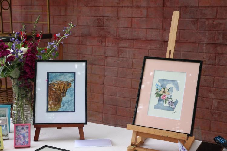 Christi Fordyce, who lives in Arnoldsville, had multiple watercolor drawings of various flowers and wildlife on display at the book sale and art show on Saturday. The Scottish highland cow painting was among a few that sold for $25. The cost of the tables, which was $20, goes to the library. The profits go to the artists. (Photo/Olivia Wilson)