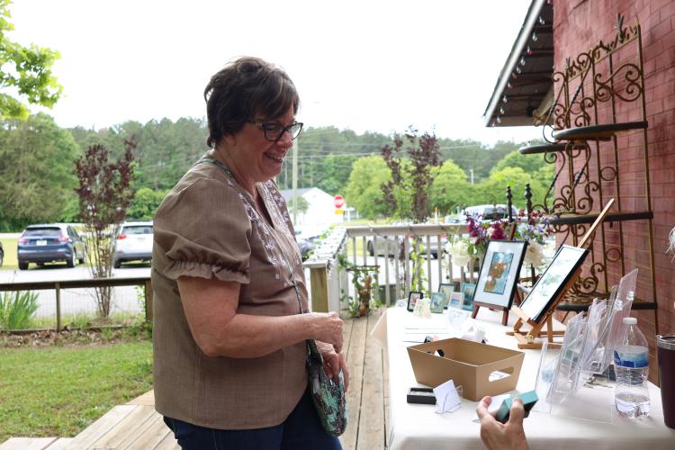 Donna Brooks of Arnoldsville purchased a small flower watercolor painting at the art show on Saturday, May 3. The small watercolor painting with frames sold for $5. (Photo/Olivia Wilson)