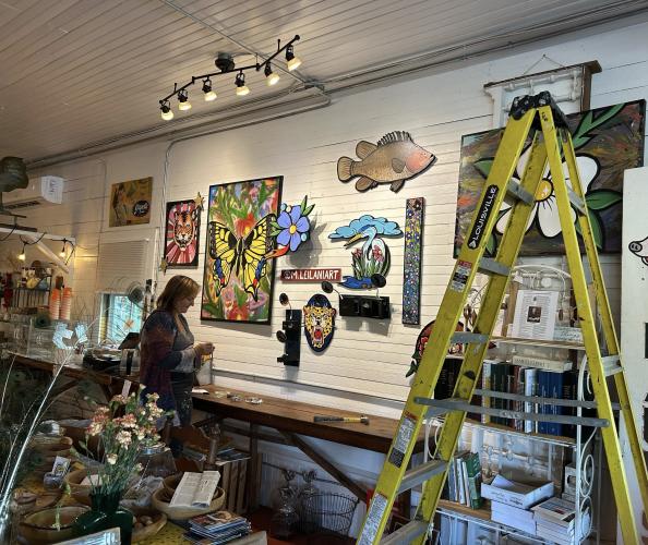 Marisa Mustard, who painted the mural on the outside of Lexington’s Rowdy Rooster, adds finishing touches to her art display inside the building. The exhibit will be on display until mid-June. (Submitted Photo)