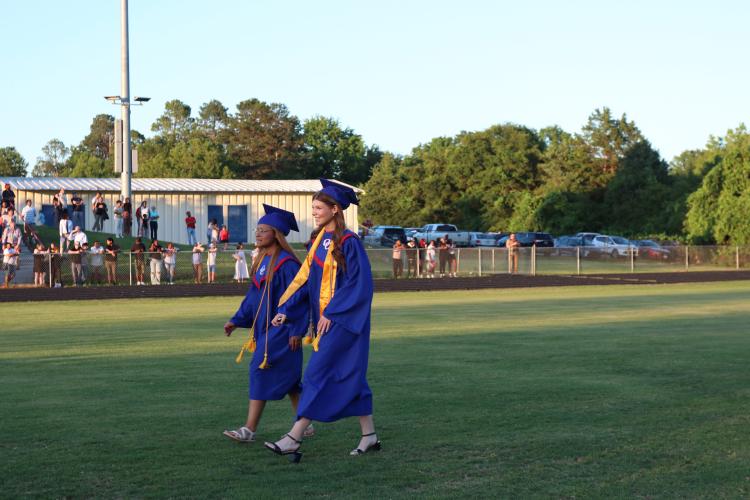 Nyah McAphee and Sophia Wilson walk onto the Patriot Stadium field for graduation last Friday. They were two of the 150 students to receive their diplomas. (Photo/Anna Izquierdo)