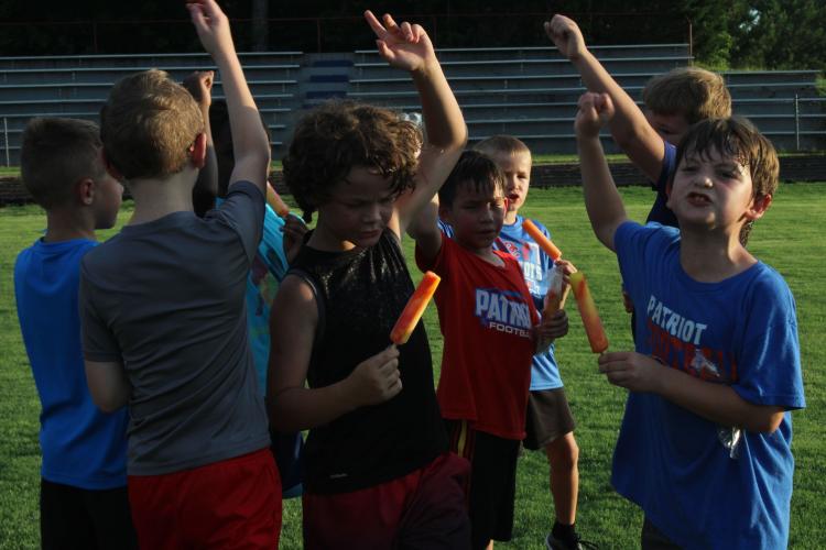 Campers celebrate the end of the OCHS Youth Football Camp and all of their hard work with popsicles and cheer for the Patriots. (Photo/Elizabeth Kim)