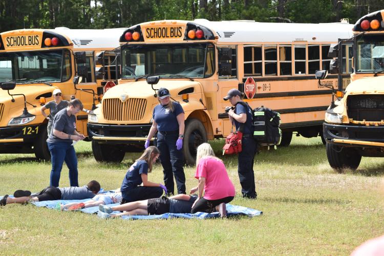 Oglethorpe County's Emergency Management Agency hosted a mass casualty exercise on Saturday. First responders evaluate volunteer students who have been pulled from a nearby school bus that was flipped for the exercise. (Photo/Emma Greene)