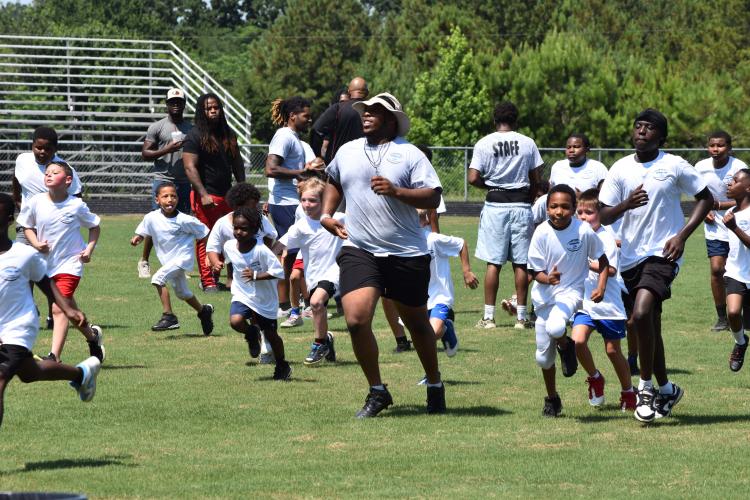 KB Bonds, a former OCHS lineman who plays for Shorter University, leads campers through drills at his football camp at OCHS on Saturday. Bonds had 24 tackles, one-half of a sack and recovered a fumble for Shorter last fall. (Photo/Emma Greene)