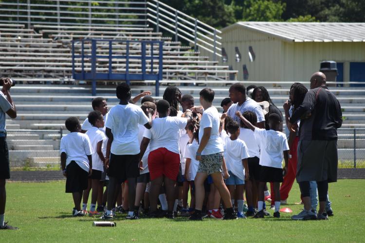 Kids participating in the KB Bonds Football Camp gather around Bonds and other coaches during a session on Saturday. The camp was for ages 6-16. (Photo/Emma Greene)
