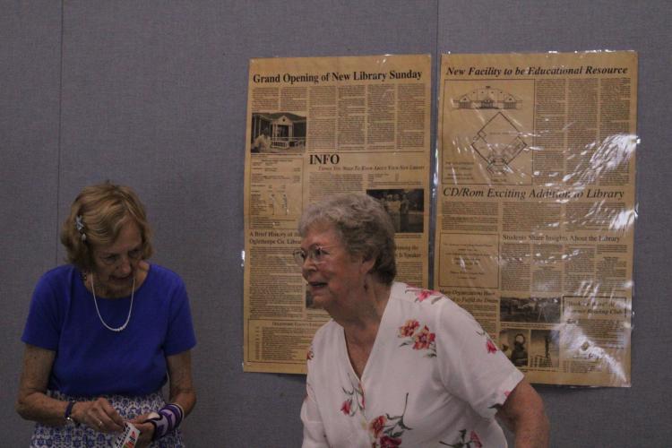 Former staff, board members and volunteers, including Peggy Hroma (left) and Jane Bowen (right), share memories of when the library opened in 1995. Articles from The Echo announcing the construction and opening of the library give information on the building’s cost and resources available to the public. (Photo/Elizabeth Kim)