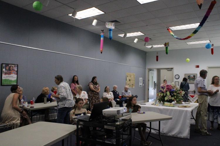 Members of the library community and staff share cake and memories to celebrate the building's 30th anniversary. Many attendees were past staff and board members, with some being present for the library's opening in 1994. (Photo/Elizabeth Kim)