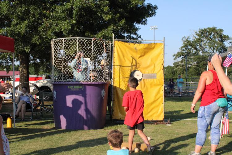 County administrator Jason Lewis is dunked at a booth hosted by the Arnoldsville Fire Department at the Fourth of July celebration at Bryan Park. “Our community is very blessed with public service,” event organizer Tina White said. “If you look around, our EMS group is here, the fire departments participate and our Sheriff's (Office) always has a big presence. They do a really good job, 365 days a year, of keeping us safe.” (Elizabeth Kim)