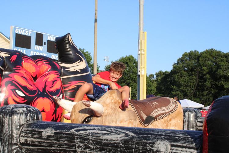 A mechanical bull bucks off a determined rider at the Fourth of July celebration. Families with kids of all ages were able to play, eat and enjoy the fireworks. (Elizabeth Kim)