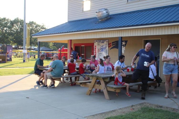 Attendees enjoy snacks and drinks in the shade of the field house at Bryan Park. A range of food options was available at the festival and included pizza, boiled peanuts, Salvadorian pupusas and funnel cakes. (Photo/Elizabeth Kim)