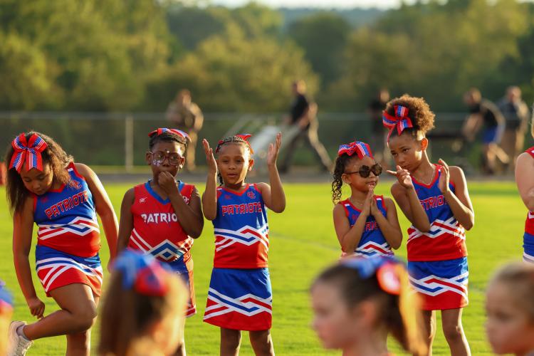 Mini cheerleaders stand in line formation to welcome the Patriots football team out onto the field for the home game on Saturday, Aug. 23. (Photo/Emma Peterson)
