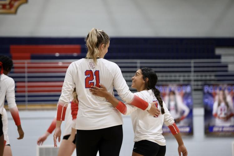 Oglethorpe County libero Aryana Knight (right), who is 4-foot-9, shows her height difference with teammate Elizabeth Cook, who is listed at 6 feet, during a match last fall. Knight is one of the Patriots’ top defenders. (Photo/Ty Johnston)