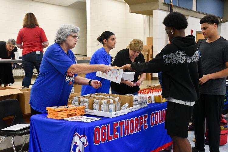 (Left to right) Board of Education member Susan Robinson, volunteer Adi Ames and Superintendent Beverley Levine pass out school supplies to students at this year's Community Day at Oglethorpe County Middle School on Saturday. The annual event provides community resources to families as students head back to school for the year. (Photo/Jennifer Xia)