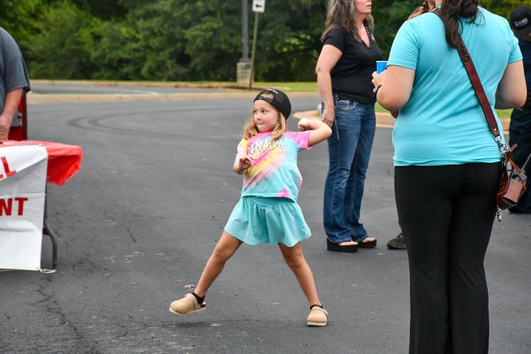 Second-grader Elyza Echols winds up to throw a baseball to try to dunk OCHS band director Lee Jones. The dunk tank was hosted by the Pleasant Hill Volunteer Fire Department at Community Day on Saturday. About 350 people attended the event. (Photo/Jennifer Xia)