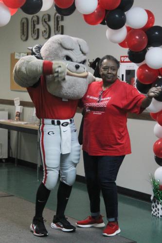 Oglethorpe County Senior Center member Janice Brown dances with Hairy Dawg before getting a photo at the center's tailgate party on Friday. Brown visits the center about three times a week and looks forward to seeing everybody. (Hannah Freeman/The Oglethorpe Echo)