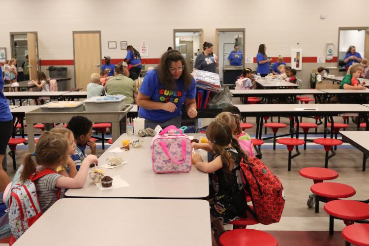 Pre-K teacher Kelli Kitchen helps students with their breakfast items during the first day of school Aug. 1. (Photo/Anna Izquierdo)